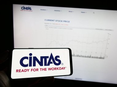 Stuttgart, Almanya: 06-25-2023: Aemrican şirketi Cintas Corporation 'ın logosuyla cep telefonu sahibi kişi iş sayfasının önünde ekranda. Telefon ekranına odaklan.