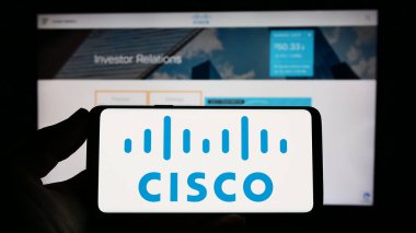 Stuttgart, Almanya: 06-25-2023: ABD 'li iletişim şirketi Cisco Systems Inc.' nin logosuyla cep telefonu sahibi kişi web sayfası önünde ekranda. Telefon ekranına odaklan.