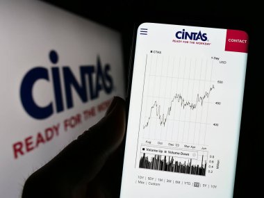 Stuttgart, Almanya: 06-25-2023: ABD 'li Cintas Corporation şirketinin web sayfası ile cep telefonu sahibi kişi iş logosu önünde ekranda. Telefon ekranının merkezine odaklan.