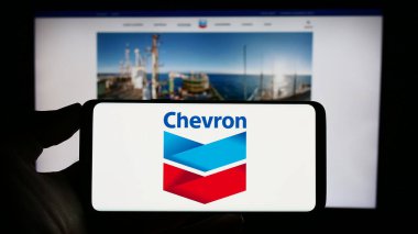 Stuttgart, Almanya: 06-25-2023: ABD 'li enerji şirketi Chevron Corporation' ın logosuyla cep telefonu sahibi kişi iş sayfasının önünde ekranda. Telefon ekranına odaklan.