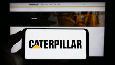 Stuttgart, Almanya - 06-25-2023: Amerikan ağır ekipman şirketi Caterpillar Inc. 'in logosuna sahip cep telefonu web sayfasının önünde ekranda. Telefon ekranına odaklan.