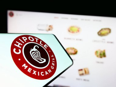 Stuttgart, Almanya - 06-25-2023: İnternet sitesinin önünde ekranda Chipotle Mexican Grill Inc. 'in logosuna sahip cep telefonu. Telefon ekranının merkez sağına odaklan.