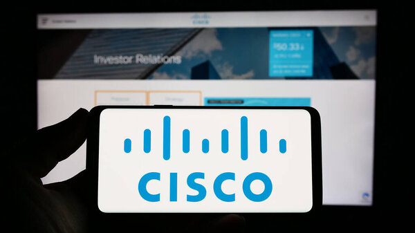 Stuttgart, Germany : 06-25-2023: Person holding cellphone with logo of US communications company Cisco Systems Inc. on screen in front of web page. Focus on phone display.