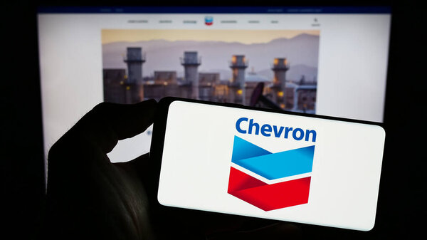 Stuttgart, Germany : 06-25-2023: Person holding smartphone with logo of US energy company Chevron Corporation on screen in front of website. Focus on phone display.