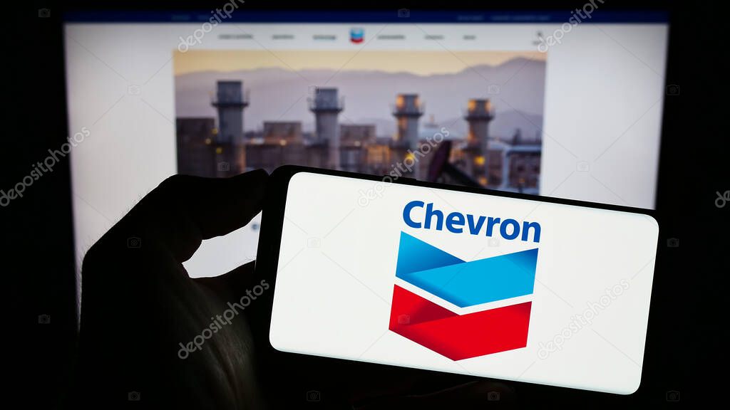 Stuttgart, Germany : 06-25-2023: Person holding smartphone with logo of US energy company Chevron Corporation on screen in front of website. Focus on phone display.