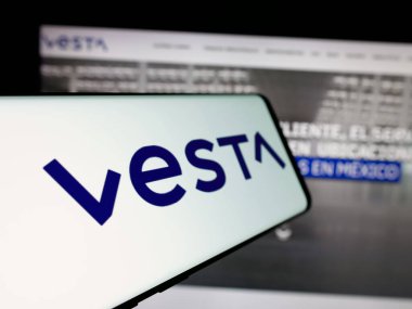 Stuttgart, Almanya - 11-11-2024: Şirket logosu olan cep telefonu Inmobiliaria Vesta S.A.B. De C.V. iş sitesinin önünde ekranda. Telefon ekranının soluna odaklan.
