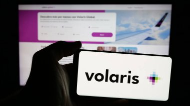 Stuttgart, Almanya - 11-11-2024: Meksikalıların düşük maliyetli havayolu şirketi Volaris 'in logosunu taşıyan cep telefonu sahibi kişi iş sayfasının önünde ekranda. Telefon ekranına odaklan.