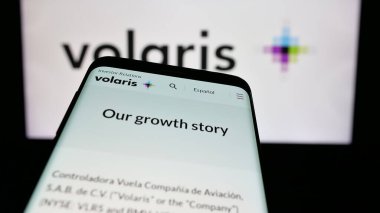 Stuttgart, Germany - 11-11-2024: Smartphone with website of Mexian low-cost airline company Volaris on screen in front of business logo. Focus on top-left of phone display. clipart