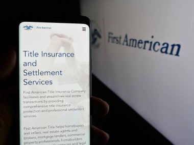 Stuttgart, Almanya - 11-11-2024: ABD 'li First American Financial Corporation' ın web sayfası olan akıllı telefon sahibi kişi ekranda ABD logosunda. Telefon ekranının merkezine odaklan.