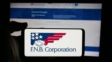 Stuttgart, Almanya - 11-13-2024: Web sayfası önünde ABD 'li FNB Corporation (First National Bank) logosunun bulunduğu cep telefonu sahibi kişi. Telefon ekranına odaklan.