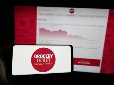 Stuttgart, Almanya - 11-14-2024: ABD 'li perakende şirketi Market Holding Corp' un logosuna sahip akıllı telefon sahibi kişi web sitesi önünde ekranda. Telefon ekranına odaklan.