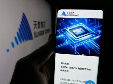 Stuttgart, Almanya - 11-14-2024: Çinli teknoloji şirketi Iluvatar CoreX 'in web sayfası ile logo önünde cep telefonu tutan kişi. Telefon ekranının merkezine odaklan.