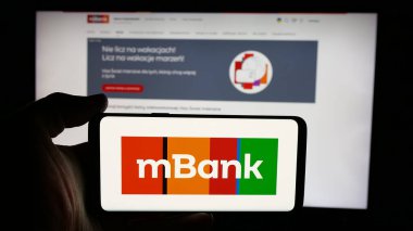 Stuttgart, Almanya - 11-26-2024: Polonyalı bankacılık şirketi mBank S.A. 'nın logosuyla cep telefonu sahibi kişi iş sayfasının önünde ekranda. Telefon ekranına odaklan.