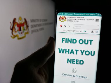 Stuttgart, Almanya - 11-25-2024: Ajans İstatistik Dairesi Malezya (DOSM) web sayfası ile cep telefonu tutan kişi logolu ekranda. Telefon ekranının merkezine odaklan.
