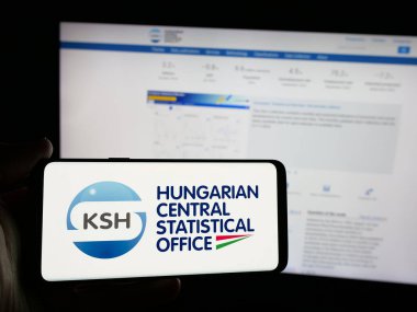 Stuttgart, Almanya - 11-25-2024: İnternet sitesi önünde üzerinde Macaristan Merkez İstatistik Ofisi (KSH) logosu bulunan akıllı telefon sahibi kişi. Telefon ekranına odaklan.
