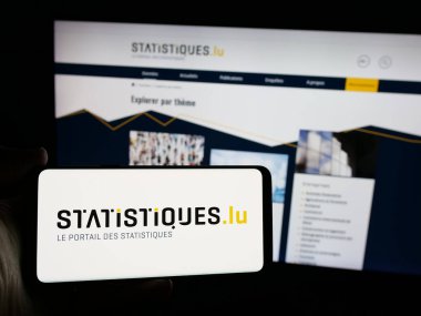 Stuttgart, Almanya - 11-24-2024: Lüksemburg istatistik dairesi STATEC 'in logosuna sahip akıllı telefon sahibi kişi web sitesi önünde ekranda. Telefon ekranına odaklan.