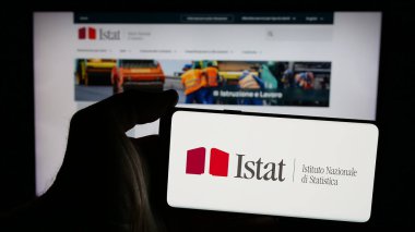 Stuttgart, Almanya - 11-21-2024: İnternet sayfasının önünde ekranda İtalyan Istituto Nazionale di Statistica (Istat) logosu bulunan cep telefonu sahibi kişi. Telefon ekranına odaklan.