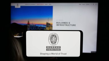 Stuttgart, Almanya - 11-20-2024: Fransız sertifika şirketi Bürosu Veritas SA 'nın logosuyla cep telefonu sahibi kişi iş sayfasının önünde ekranda görülüyor. Telefon ekranına odaklan.
