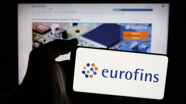 Stuttgart, Almanya - 11-18-2024: Laboratuvar şirketi Eurofins Scientific SE 'nin logosunun bulunduğu cep telefonu sahibi kişi iş sayfasının önünde ekranda. Telefon ekranına odaklan.