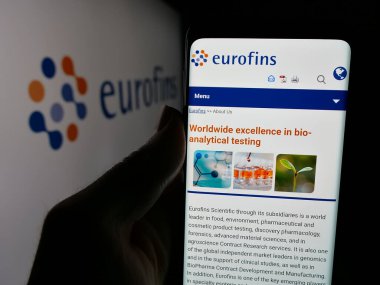 Stuttgart, Almanya - 11-18-2024: Laboratuvar şirketi Eurofins Scientific SE 'nin web sitesi ile akıllı telefonu olan kişi logo önünde ekranda. Telefon ekranının merkezine odaklan.