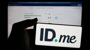 Stuttgart, Almanya - 11-18-2024: Üzerinde Amerikan kimlik doğrulama şirketinin logosu olan cep telefonu sahibi kişi web sayfasının önünde ekranda. Telefon ekranına odaklan.