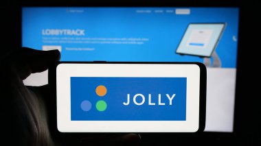 Stuttgart, Almanya - 11-15-2024: Yazılım şirketi Jolly Technologies Inc. 'in logosuyla cep telefonu sahibi kişi iş sayfasının önünde ekranda. Telefon ekranına odaklan.