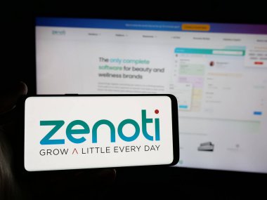 Stuttgart, Almanya - 11-15-2024: Web sitesi önünde ekranda, üzerinde ABD 'li güzellik yazılım şirketi Soham Inc. (Zenoti) logosu olan akıllı telefon bulunan kişi. Telefon ekranına odaklan.