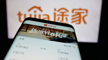 Stuttgart, Almanya - 11-15-2024: Çinli emlak platformu şirketi Tujia 'nın web sitesi ile cep telefonu iş logosu önünde ekranda. Telefon ekranının sol üst kısmına odaklan.