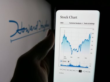 Stuttgart, Almanya - 11-26-2024: ABD 'li gayrimenkul şirketi Howard Hughes Holding Inc.' nin web sayfası ile cep telefonu sahibi kişi logolu ekranda. Telefon ekranının merkezine odaklan.
