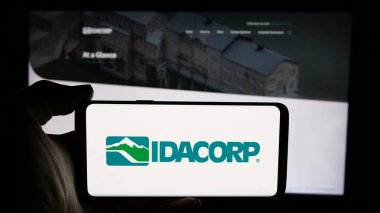 Stuttgart, Almanya - 11-26-2024: ABD 'li elektrik şirketi IDACORP Inc.' in logosuyla cep telefonu sahibi kişi iş sayfasının önünde ekranda. Telefon ekranına odaklan.