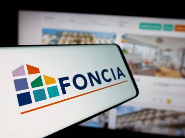 Stuttgart, Almanya - 11-26-2024: Fransız emlak şirketi Foncia SAS 'ın logosunu taşıyan akıllı telefon iş sitesinin önünde ekranda. Telefon ekranının soluna odaklan.