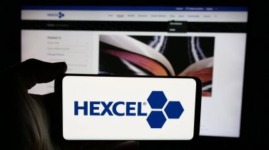 Stuttgart, Almanya - 11-26-2024: Amerikan malzeme şirketi Hexcel Corporation 'ın logosuyla cep telefonu sahibi kişi iş sayfasının önünde ekranda. Telefon ekranına odaklan.