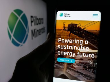 Stuttgart, Almanya - 11-28-2024: Avustralyalı maden şirketi Pilbara Minerals Limited 'in web sayfası ile cep telefonu tutan kişi logolu ekranda. Telefon ekranının merkezine odaklan.