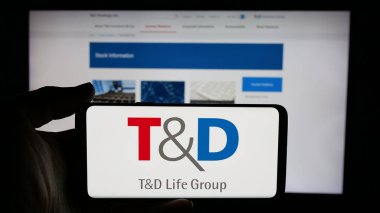 Stuttgart, Almanya - 11-28-2024: Japon sigorta şirketi TD Holding 'in logosuyla cep telefonu sahibi kişi iş sayfasının önünde ekranda. Telefon ekranına odaklan.