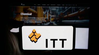 Stuttgart, Almanya - 11-28-2024: ABD 'li endüstriyel imalat şirketi ITT Inc.' in logosuyla cep telefonu sahibi kişi iş sayfasının önünde ekranda. Telefon ekranına odaklan.