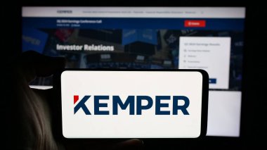 Stuttgart, Almanya - 11-28-2024: ABD 'li sigorta şirketi Kemper Corporation' ın logosuyla cep telefonu sahibi kişi iş sayfasının önünde ekranda. Telefon ekranına odaklan.