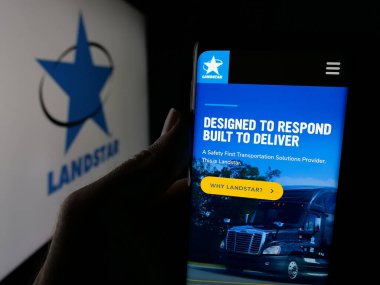 Stuttgart, Almanya - 11-28-2024: ABD 'li ulaşım şirketi Landstar System Inc.' in internet sayfası ile cep telefonu tutan kişi logolu ekranda. Telefon ekranının merkezine odaklan.