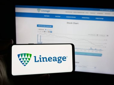 Stuttgart, Almanya - 11-28-2024: Web sitesi önünde ekranda ABD 'li depolama şirketi Lineage Inc.' in logosuna sahip akıllı telefonu tutan kişi. Telefon ekranına odaklan.