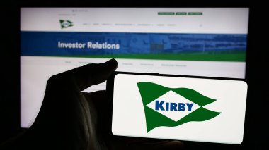 Stuttgart, Almanya - 11-28-2024: ABD 'li nakliye şirketi Kirby Corporation' ın logosuyla cep telefonu sahibi kişi iş sayfasının önünde ekranda. Telefon ekranına odaklan.