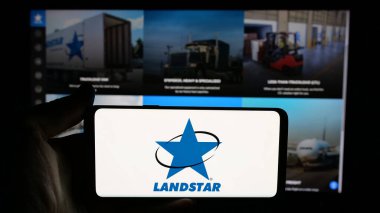 Stuttgart, Almanya - 11-28-2024: Web sayfası önünde üzerinde Amerikan ulaşım şirketi Landstar System Inc. 'in logosu bulunan cep telefonu sahibi kişi. Telefon ekranına odaklan.