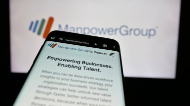 Stuttgart, Almanya - 12-02-2024: İş logosu önünde ekranda ABD 'li personel şirketi ManpowerGroup Inc.' in web sitesi bulunan cep telefonu. Telefon ekranının sol üst kısmına odaklan.
