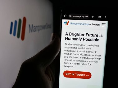 Stuttgart, Almanya - 12-02-2024: ABD 'li personel şirketi Manpower Group Inc.' nin web sayfası ile cep telefonu tutan kişi logonun önünde ekranda. Telefon ekranının merkezine odaklan.