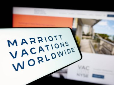 Stuttgart, Germany - 12-02-2024: Cellphone with logo of US company Marriott Vacations Worldwide Corporation on screen in front of website. Focus on center-left of phone display. clipart