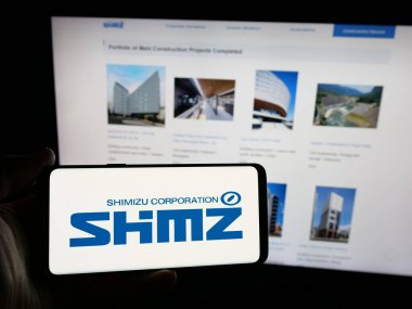 Stuttgart, Almanya - 12-03-2024: Japon mühendislik şirketi Shimizu Corporation 'ın logosunu elinde tutan kişi web sitesinin önünde ekranda. Telefon ekranına odaklan.