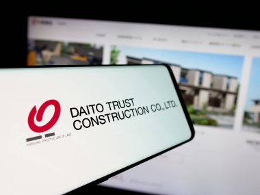 Stuttgart, Germany - 12-04-2024: Cellphone with logo of company Daito Trust Construction Company Ltd. on screen in front of business website. Focus on center-left of phone display. clipart