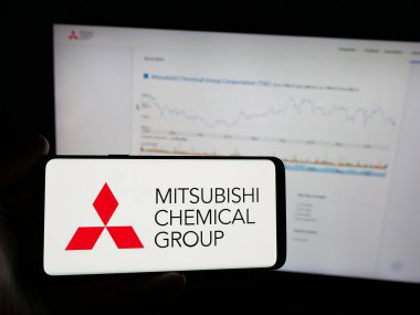 Stuttgart, Almanya - 12-05-2024: Mitsubishi Chemical Group Corporation şirketinin logosunu elinde tutan kişi web sitesinin önünde ekranda. Telefon ekranına odaklan.