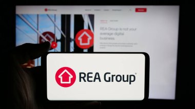 Stuttgart, Almanya - 12-05-2024: Avustralyalı emlak şirketi REA Group Limited 'in logosunun bulunduğu cep telefonu web sayfası önünde ekranda. Telefon ekranına odaklan.