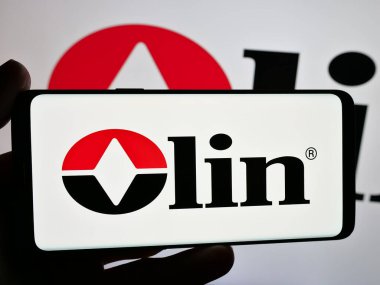 Stuttgart, Germany - 12-09-2024: Person holding smartphone with logo of US chemicals company Olin Corporation on screen. Focus on phone display. clipart