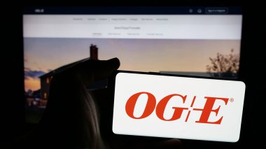 Stuttgart, Almanya - 12-09-2024: Web sayfası önünde ekranda ABD 'li Oklahoma Gas Electric Company (OGE) logosunun bulunduğu cep telefonu sahibi kişi. Telefon ekranına odaklan.