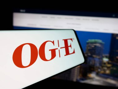 Stuttgart, Almanya - 12-09-2024: Web sitesinin önünde ekranda, üzerinde Oklahoma Gas Electric Company (OGE) logosu bulunan cep telefonu. Telefon ekranının merkez soluna odaklan.